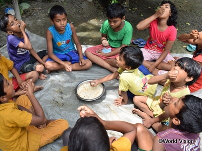 日本では「ポン菓子」の名で知られる「パフライス」を食べるバングラデシュの子どもたち