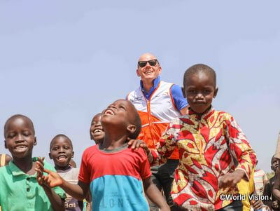 ウガンダで暮らす子どもたちとワールド・ビジョンのスタッフ